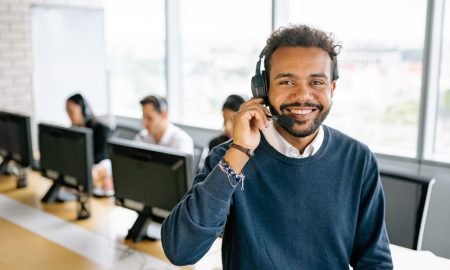 Cheerful male call center agent with headset in a bright office environment.