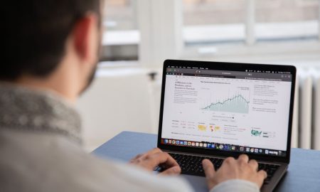 A person working on a laptop analyzing financial data in a bright indoor setting.