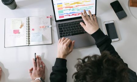 Two people collaborating on a laptop and planner at a vibrant modern office desk.