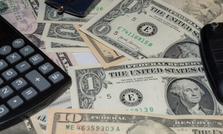 Close-up of various US banknotes, calculator, and car key illustrating finance concept.