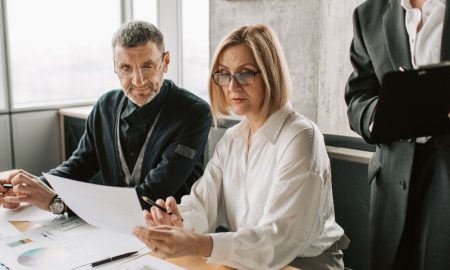 Business professionals engaged in a meeting, analyzing documents and charts in a modern office.