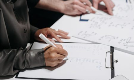 Close-up of team members taking notes and sketching designs during a meeting.