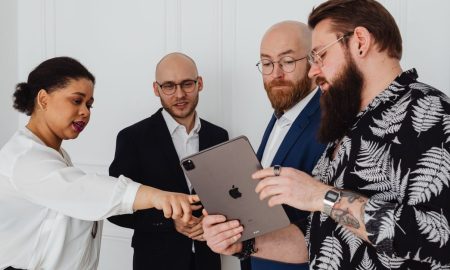 A group of diverse professionals discussing a project using a tablet in a modern office setting.
