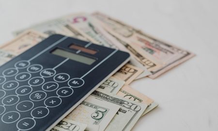 A close-up of a calculator and US dollar banknotes, symbolizing financial calculation and budgeting.