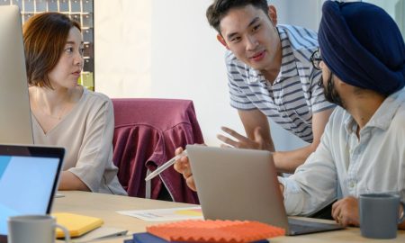 A diverse team engaged in a business meeting discussing ideas with laptops.