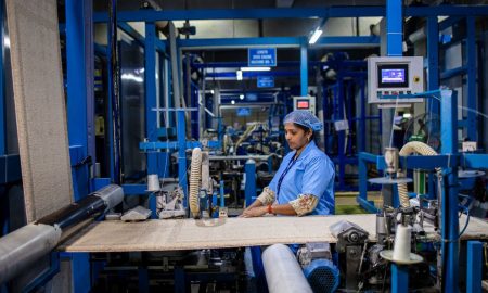 A textile factory worker operates machinery with precision, demonstrating industrial efficiency.