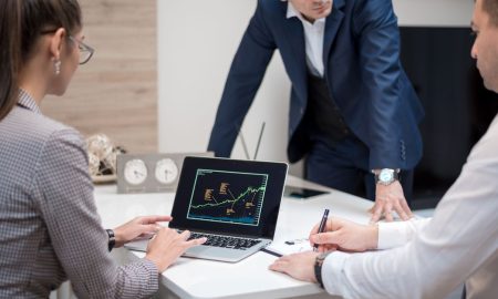 Professional team analyzing stock market trends on a laptop during a meeting.