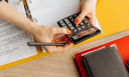 Hands using a calculator at a desk with documents and folders, ideal for finance or accounting themes.
