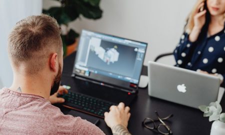 Two professionals working on laptops, engaging in a collaborative office environment.