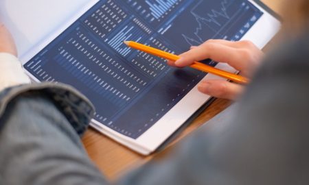 Focused image of hands analyzing business graphs and charts in a folder, highlighting data insights.