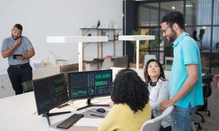 Office employees collaborate on financial data at modern workspace, engaging in teamwork and communication.