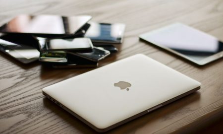 A variety of modern electronic gadgets, including a laptop and smartphones, on a wooden table.