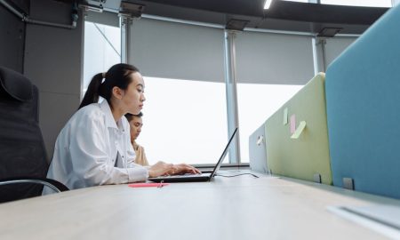 Two professionals working on laptops in a modern office setting with natural light