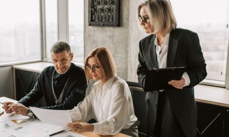 A group of business professionals discussing documents at a conference table in a modern office environment.