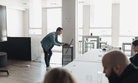 A professional presenting in a bright modern office setting to attentive colleagues.