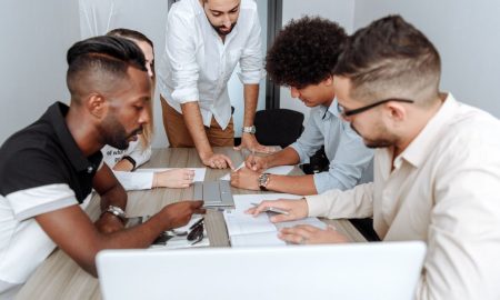 A diverse group of professionals actively collaborating at an office table during a business meeting.