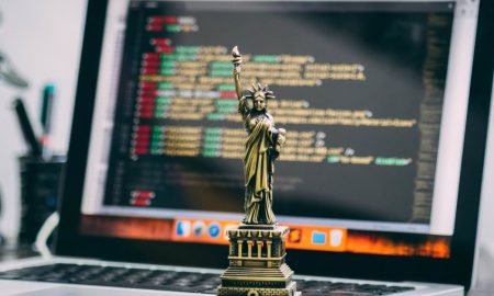 A miniature Statue of Liberty placed on a laptop displaying code, symbolizing freedom in technology.