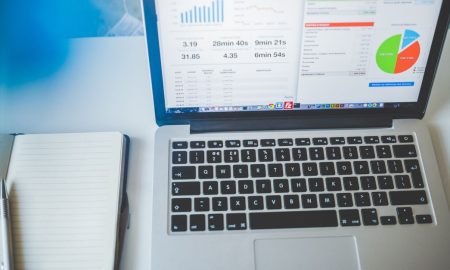 Laptop displaying charts and graphs next to a notebook, ideal for business and tech themes.