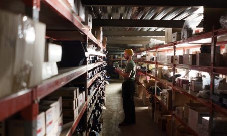 A warehouse worker sorting items on shelves in an organized storage space.