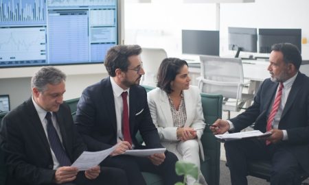 Group of business professionals discussing financial strategies in a modern office setting.