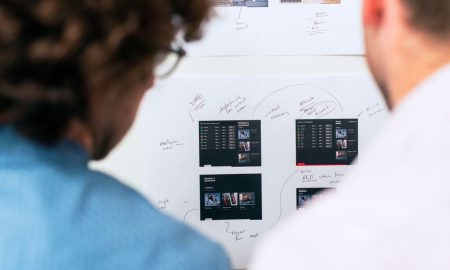 Two business professionals brainstorming and planning software development with a whiteboard in an office.