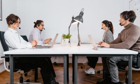 Call center team working with laptops and headsets in a modern office setting.