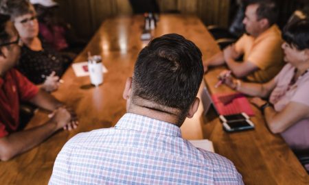 A business meeting with a diverse team discussing around a wooden table in an office setting.