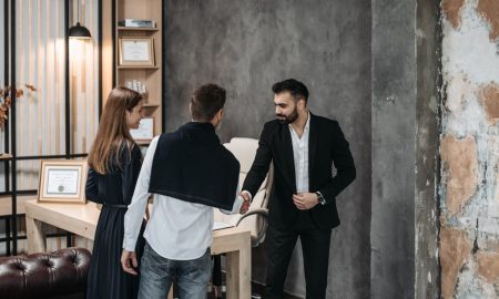 Business professionals discussing in a stylish, modern office setting with a handshake agreement.