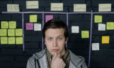 Pensive man in a startup workspace pondering tasks on a project board.